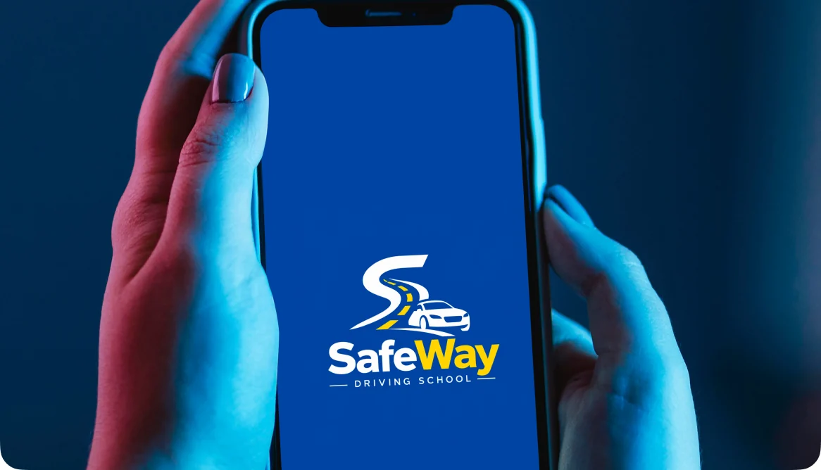 Hands holding a phone showing the Safe Way Driving School app